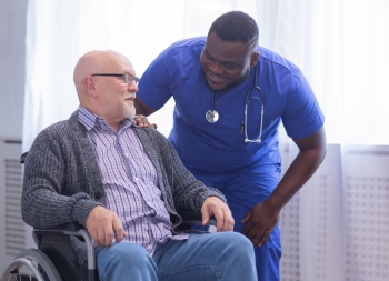 Caregiver and old man in a wheelchair. Professional nurse and patient in a nursing home. Assistance, rehabilitation and health care.